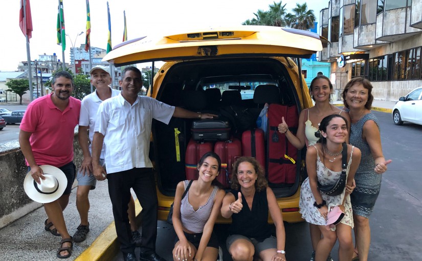 Family smiling with taxi driver in Cuba