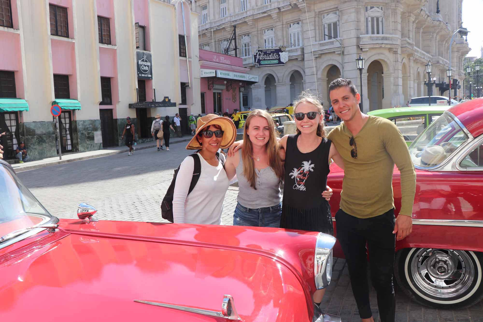 Familia junto a auto clásico rojo en La Habana, Cuba
